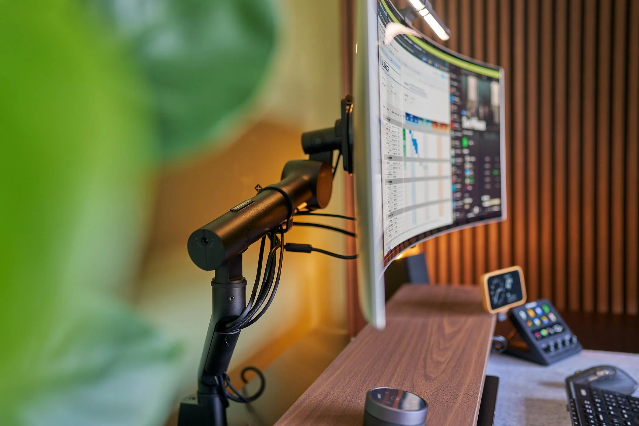 Monitorový držák Viewgo Pro od Dataflex se zakřiveným monitorem na dřevěném stole u lamelové stěny