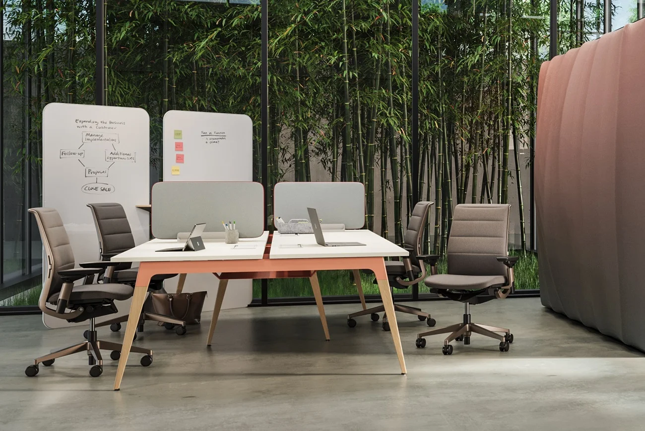 Sdílené pracoviště Steelcase s akustickými přepážkami, šedými židlemi a mobilními tabulemi u bambusu